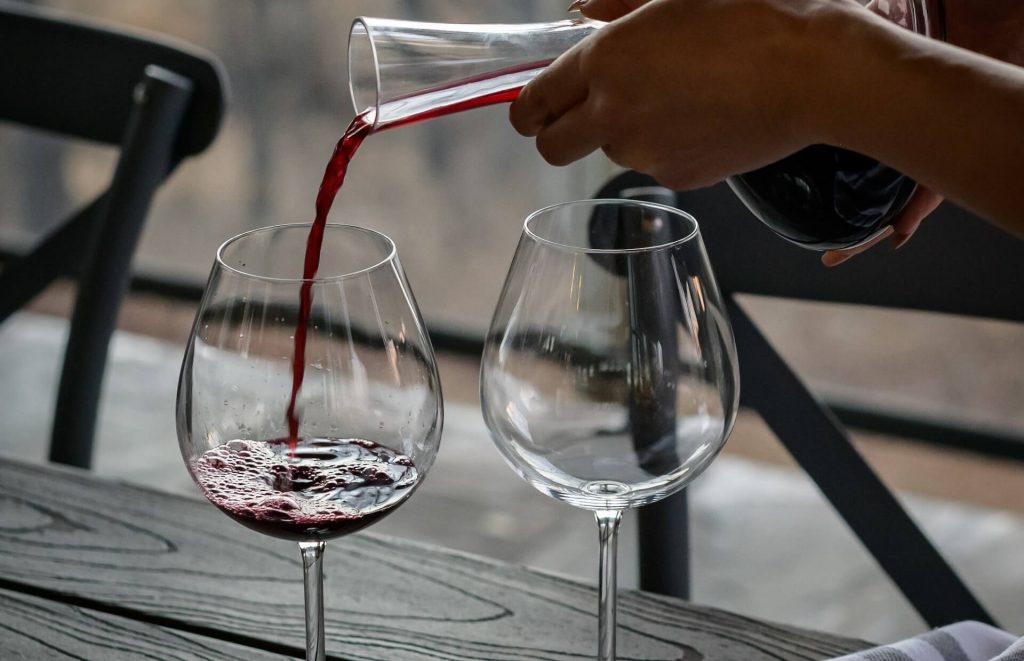 Un vino decantado siendo servido en dos copas, creando un bello espectáculo visual y anticipando una deliciosa experiencia de degustación